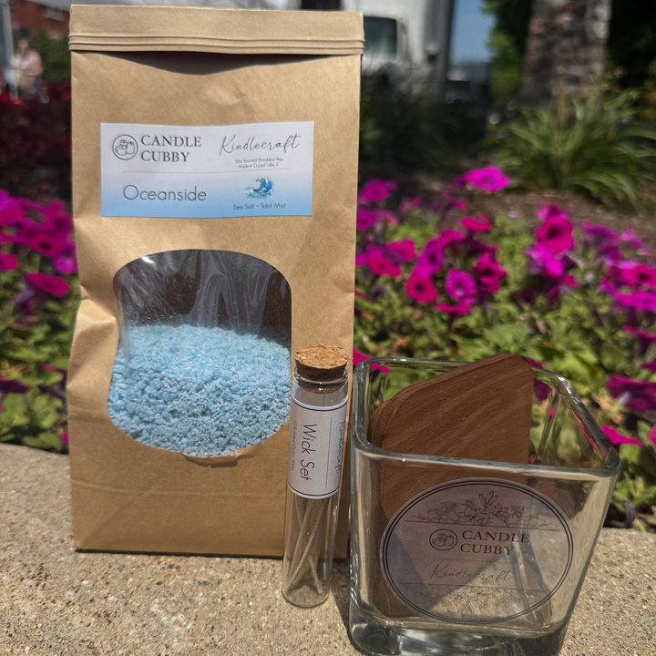 Candle Clubby product set with a bag, small bottle, and glass candle on a garden background.