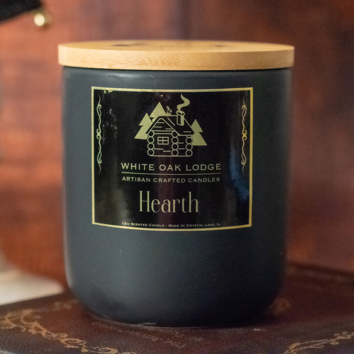 Hearth, 12oz Jar Candle, Winter Cabin Fireplace Scented, Front View on Old Books