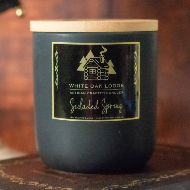 Secluded Spring, 12oz Jar Candle, Bayberry and Mossy Cypress Scented, Front View on Books